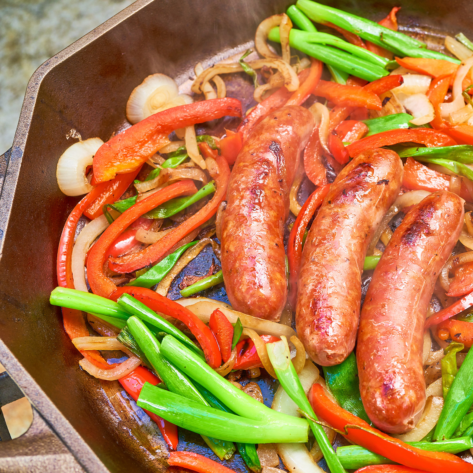 sausage cooking in skillet with onions