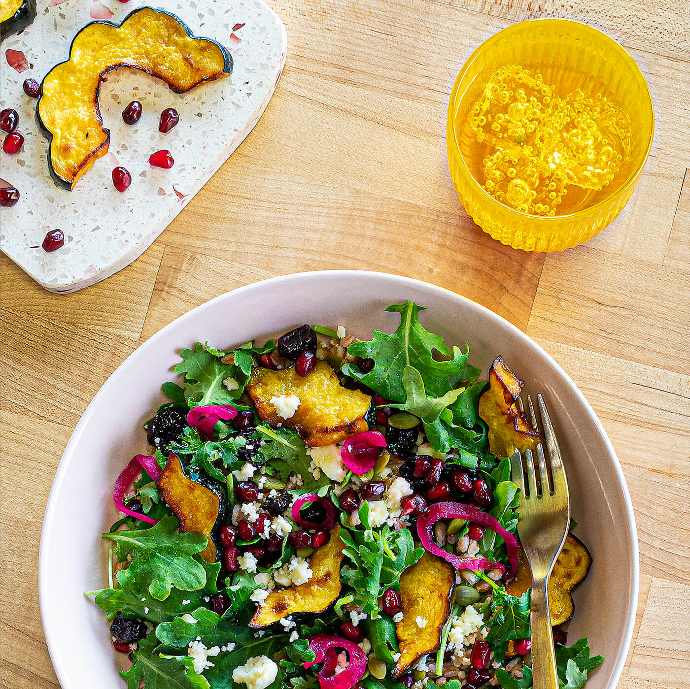 a bowl of salad with a side plate of sqaush