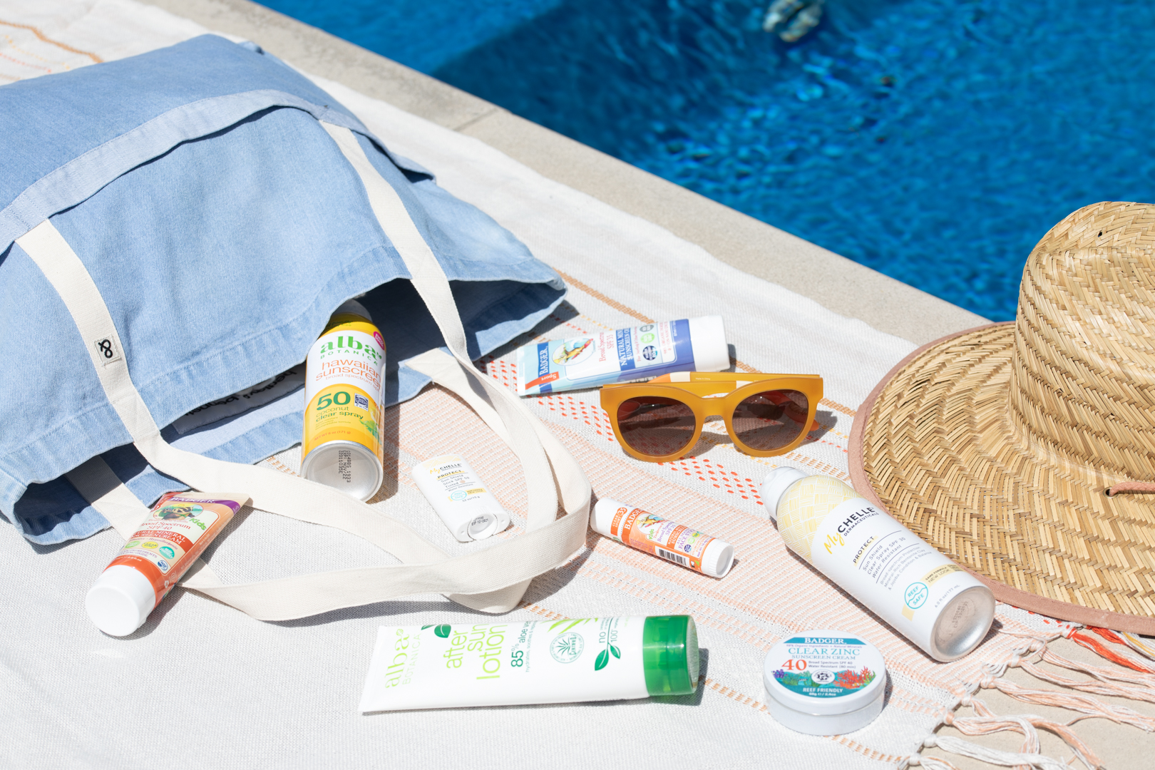 sunscreen, hat and glasses by the pool