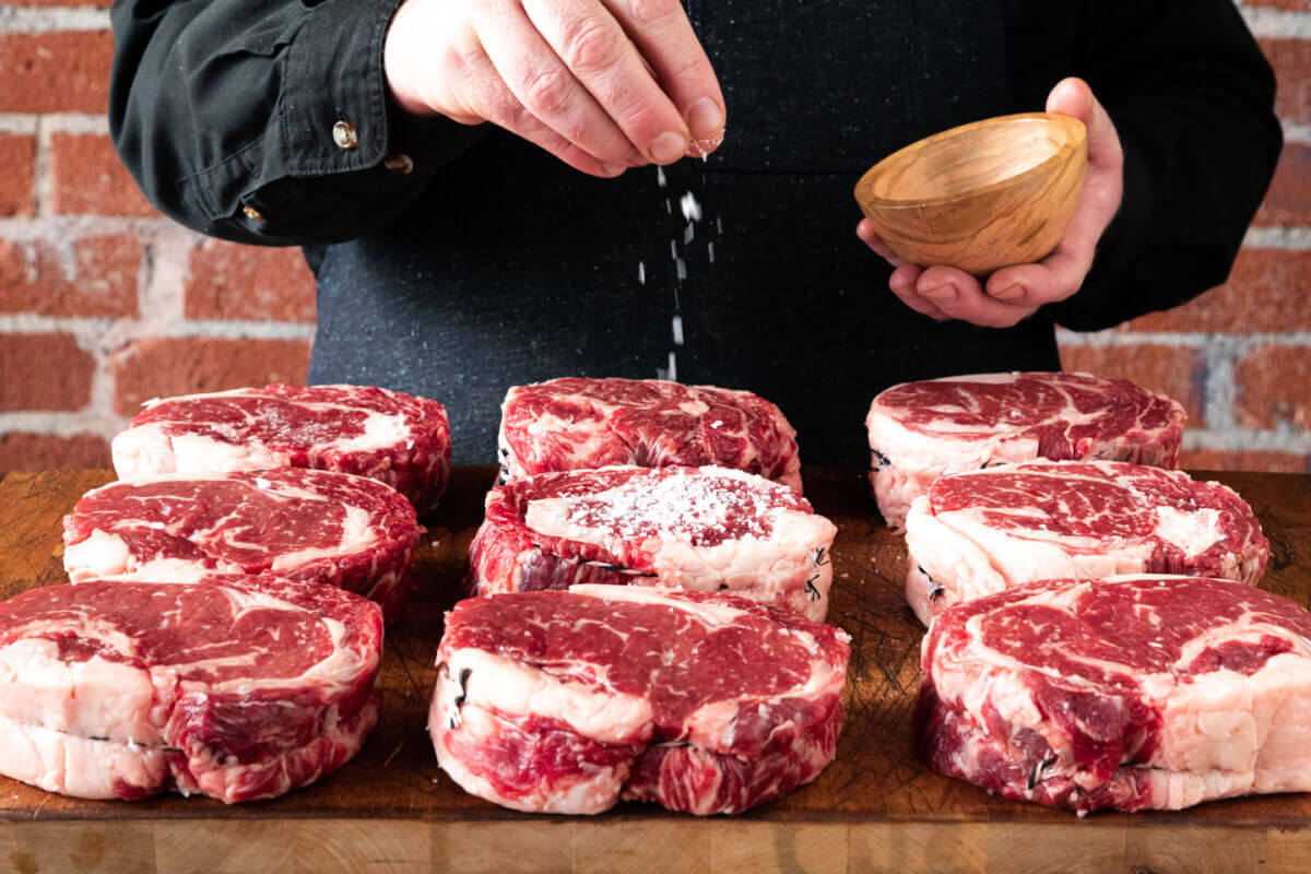 man salting steaks 